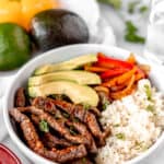 Fajita beef bowl with beef strips, peppers, cauliflower rice and avocado with text overlay.