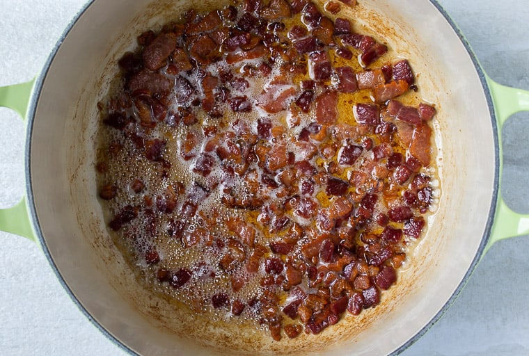 Bacon Cooking in a Dutch oven over a white background