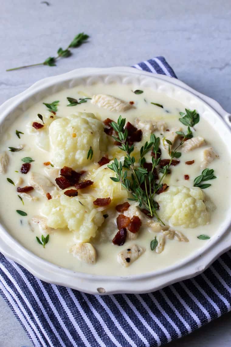 Cauliflower Chicken Chowder in a white bowl over a blue and white striped napkin on a white background