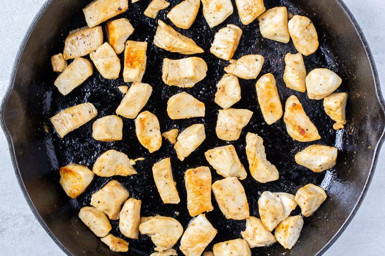 Pieces of cooked chicken in a black cast iron pan