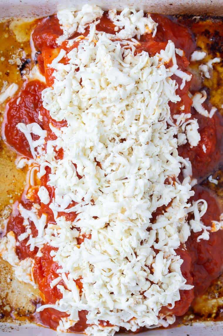 Chicken roll ups topped with tomato sauce and shredded cheese