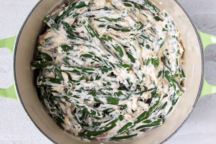 Green beans mixed with cheese mixture in a Dutch oven