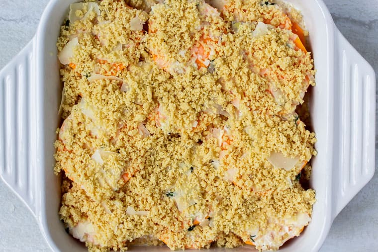 Butternut squash rounds topped with a cream sauce and almond flour breadcrumbs in a white, square baking dish