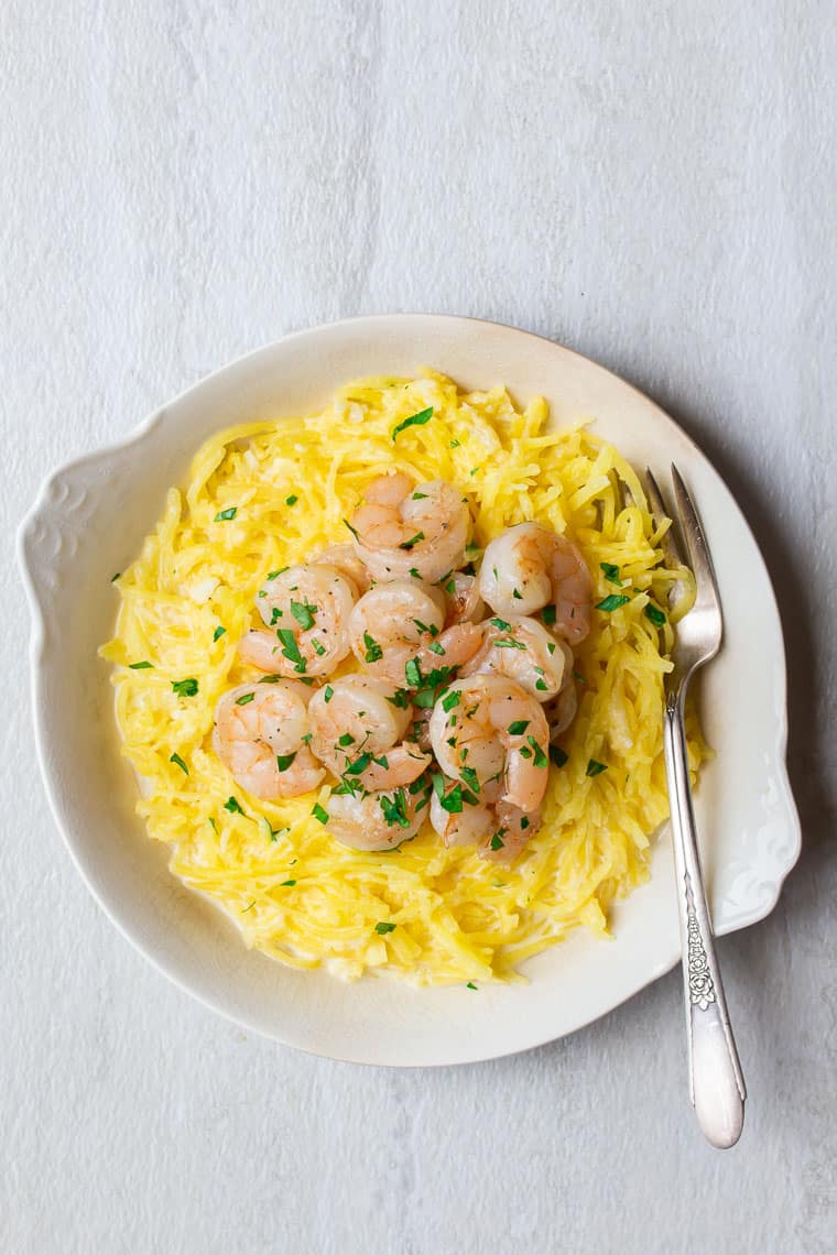Shrimp and spaghetti squash in a white bowl with a fork over a white background