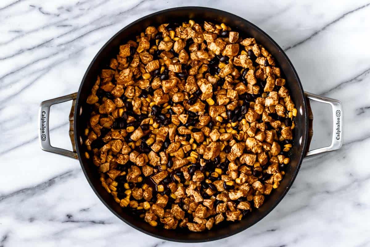 Diced chicken, spices, corn and black beans in a skillet.