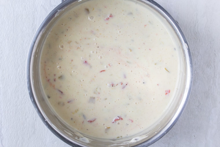 White Queso Dip with tomatoes in a silver sauce pan