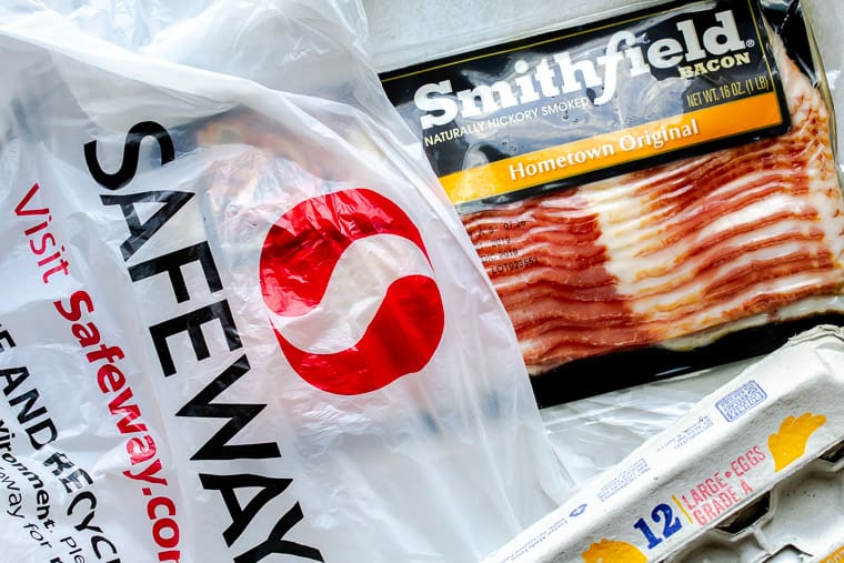 Safeway bag with a package of bacon sticking out of it and part of an egg carton off to the side