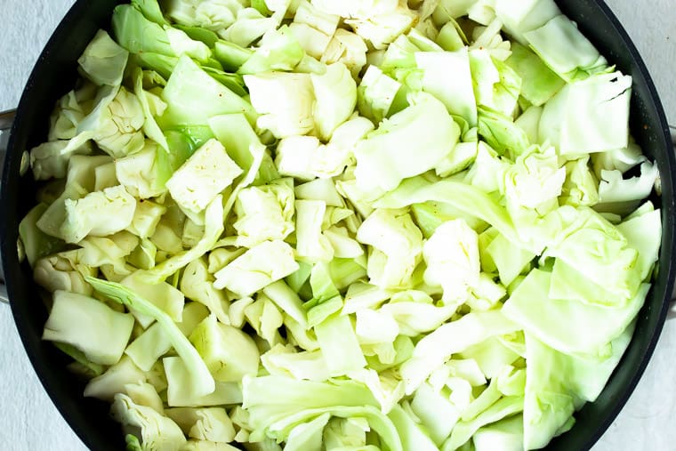Raw chopped cabbage in a black skillet