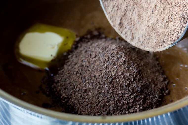 Close up of sauce pan with butter melting in chocolate pudding and grated chocolate being poured in it