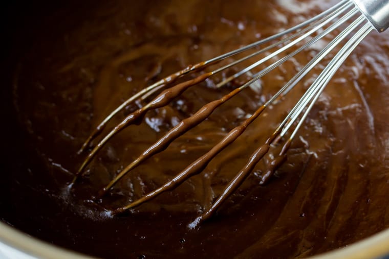 Chocolate cream pie filling close up in a saucepan with a whisk