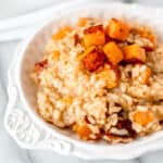 A bowl of lemon risotto with roasted butternut squash mixed in and on top of it.