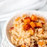 A bowl of lemon risotto with roasted butternut squash mixed in and on top of it with text overlay.