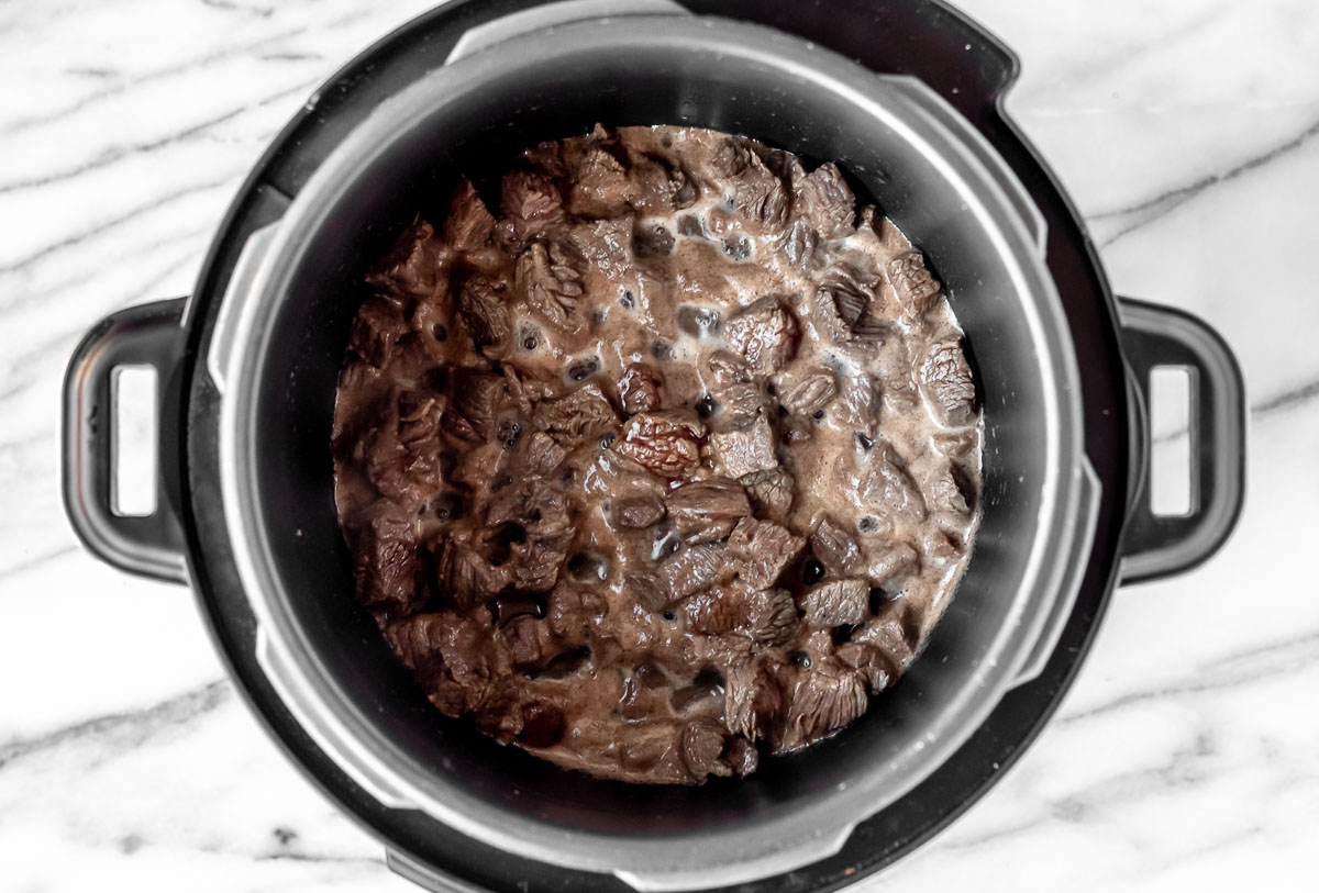 Beef cubes browned in the bottom of an Instant Pot.