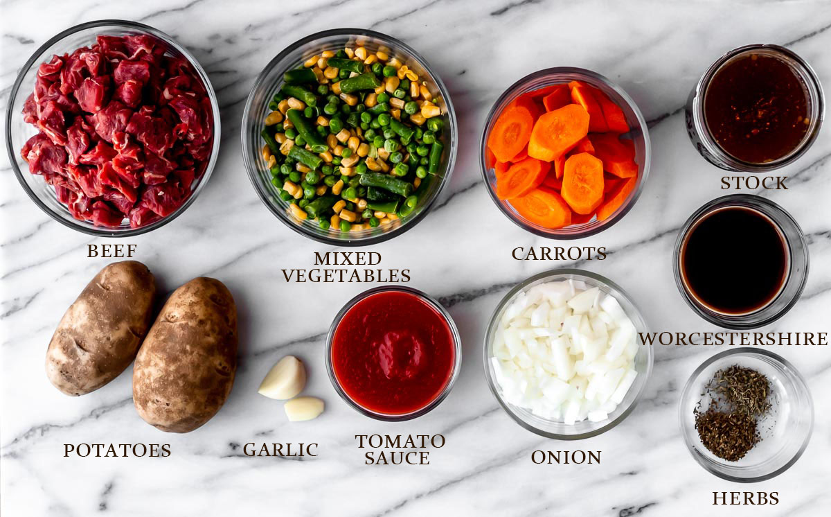 Ingredients needed to make Instant Pot Vegetable Beef Soup on a marble background with text overlay.