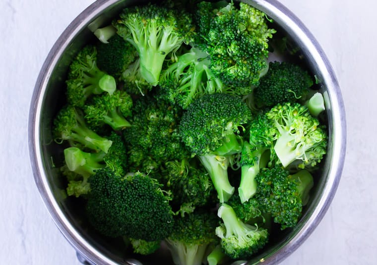 Broccoli florets in a silver pot of water