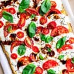Caprese Pizza on a pizza stone with parchment paper under it