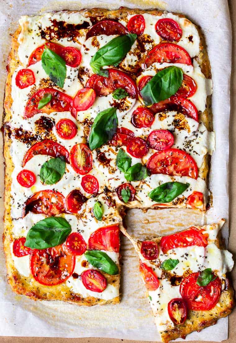 A Caprese Pizza with a slice being pulled away