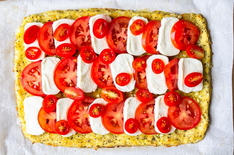 A pizza crust topped with layers of mozzarella cheese and tomatoes