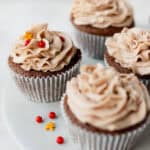 Gingerbread cupcakes decorated with gingerbread man and red sprinkles on a gray cake stand.