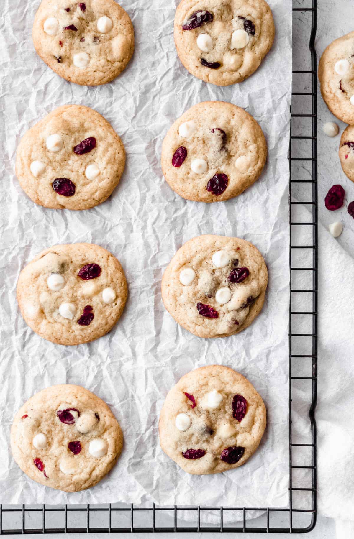 White chocolate chip cranberry cookies on parchment paper on a cooling rack