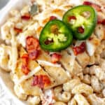 Close up of jalapeno popper chicken pasta in a white bowl with text overlay.
