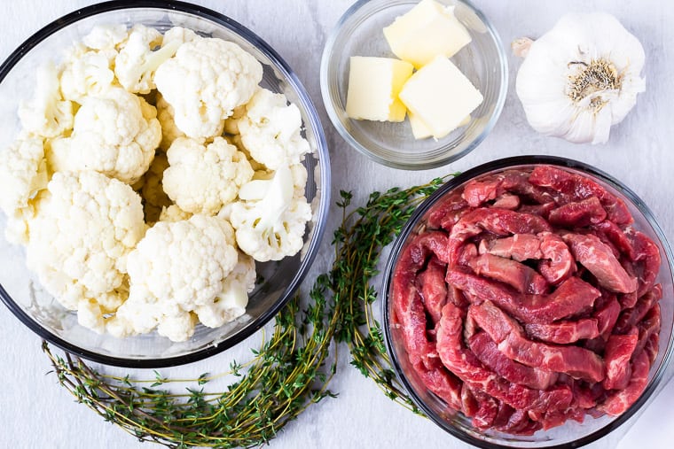 Ingredients for garlic butter steak bites in glass bowls over a white background