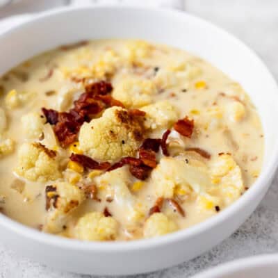 Roasted cauliflower corn chowder in a white bowl with bacon.