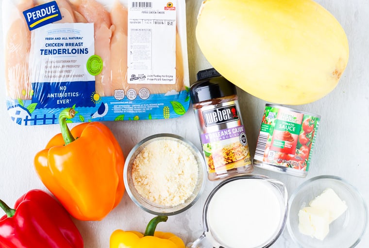 Ingredients needed to make creamy cajun chicken laid out on a white surface