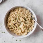 Overhead view of coconut cauliflower rice in a white bowl with a fork in it.