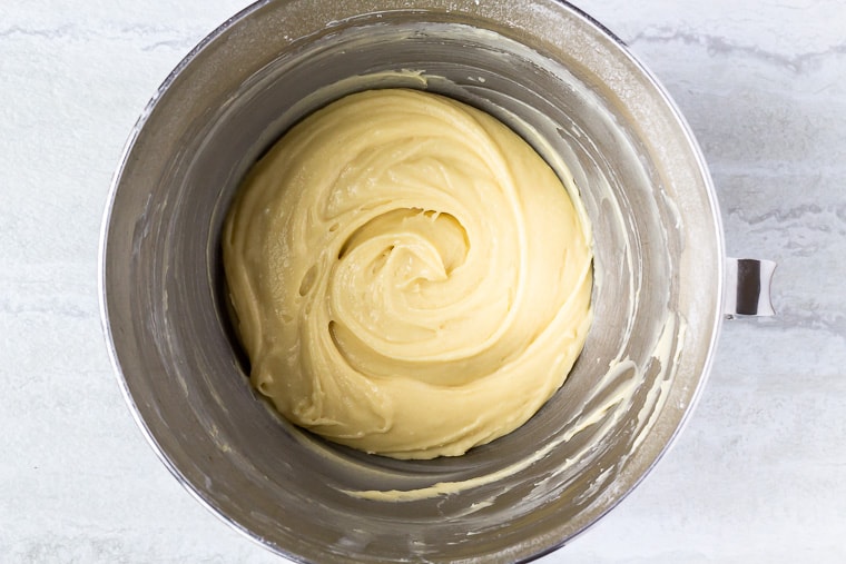Vanilla cake batter in a silver mixing bowl over a white background