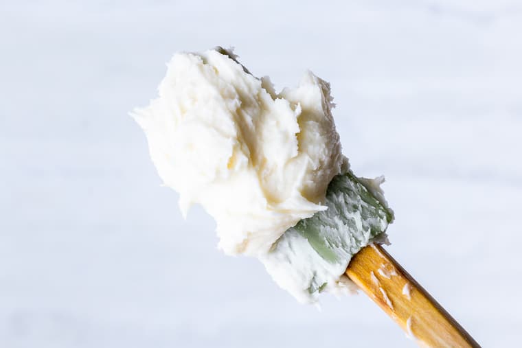 A silicone spatula holding up a scoop of homemade vanilla buttercream