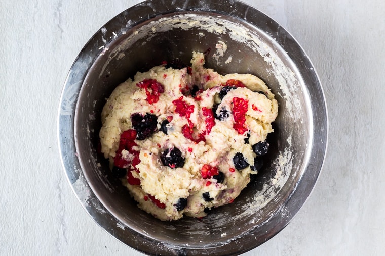 Mixed berry scones dough in a silver bowl over a white background