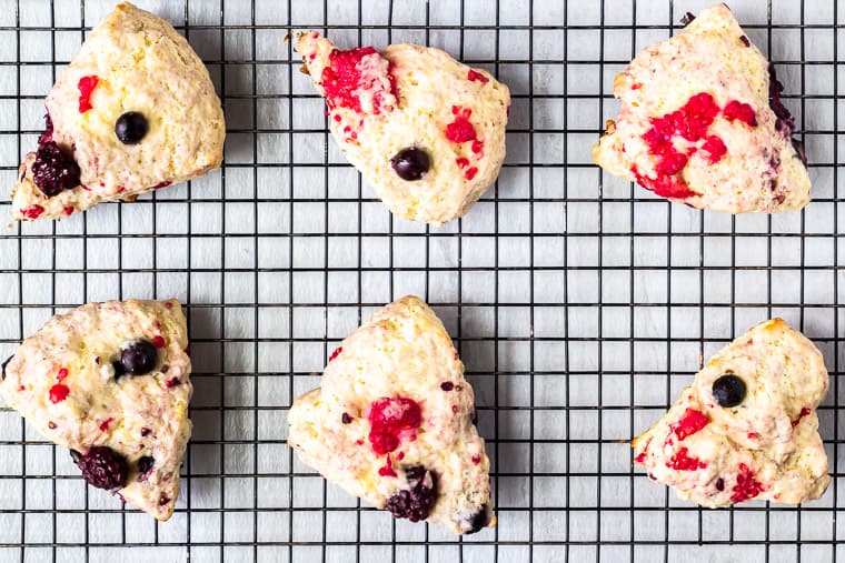 6 Mixed Berry Scones on a wire rack with a white background