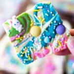 holding up a piece of white chocolate easter bark