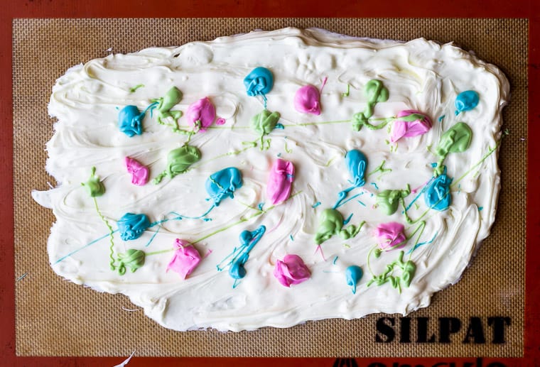 Melted white chocolate spread onto a silpat mat and topped with drops of melted candy melts