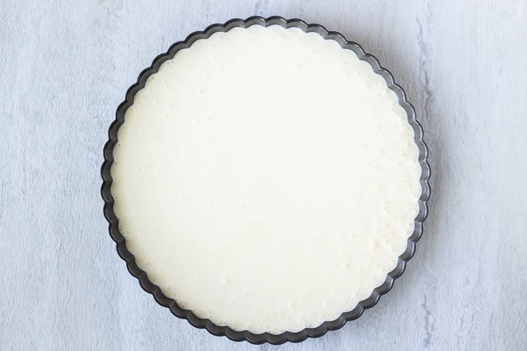 Cheesecake batter in a tart pan on a white background