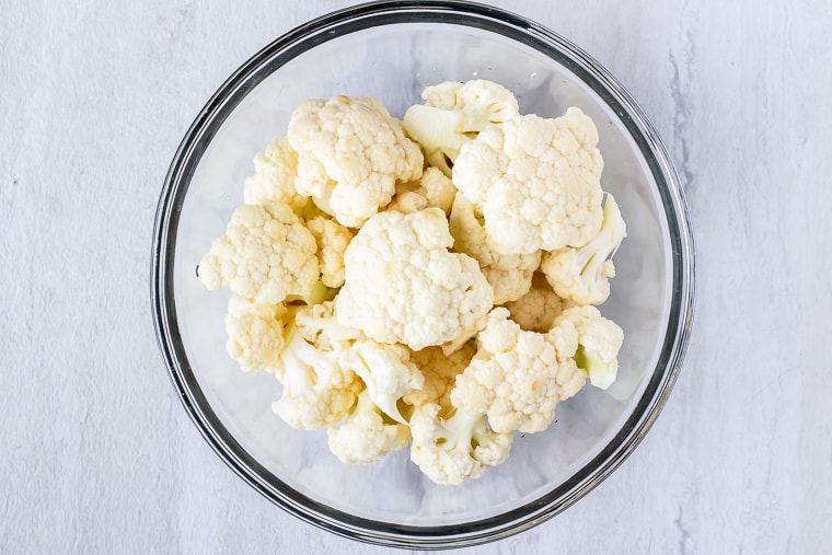 cauliflower florets in a glass bowl on a white background