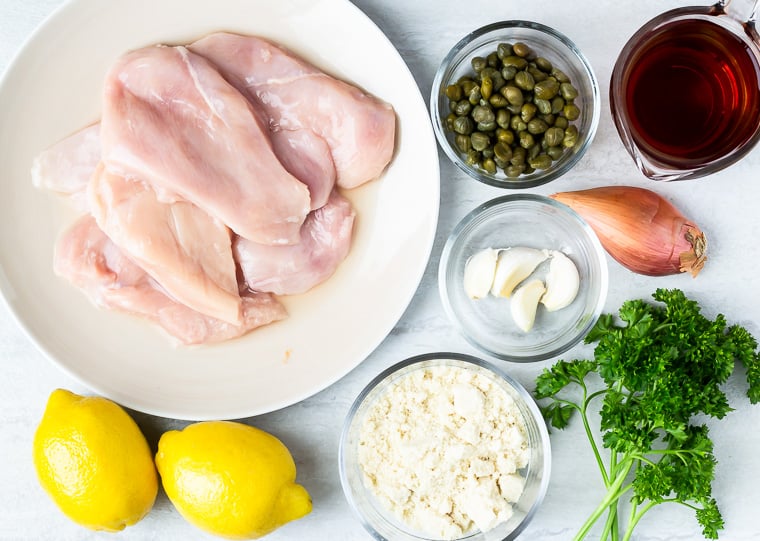 Ingredients need to make chicken piccata on a white background