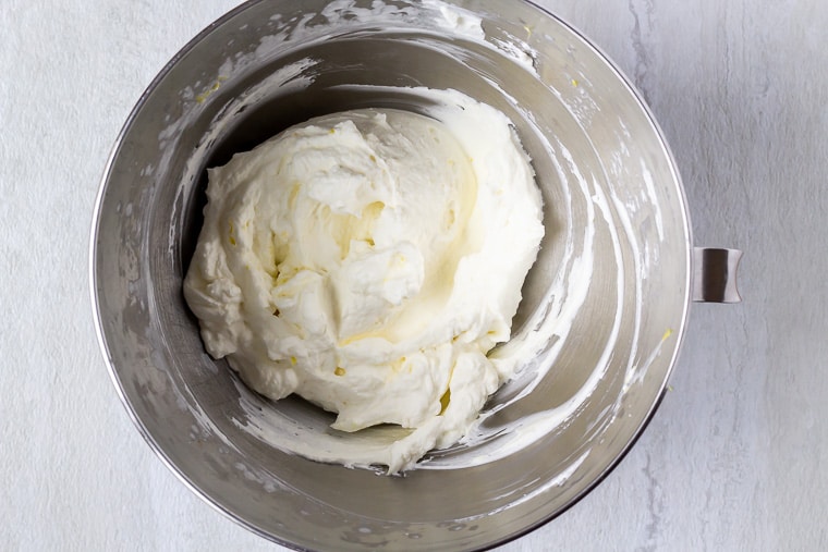 Lemon whipped cream in a silver bowl over a white background