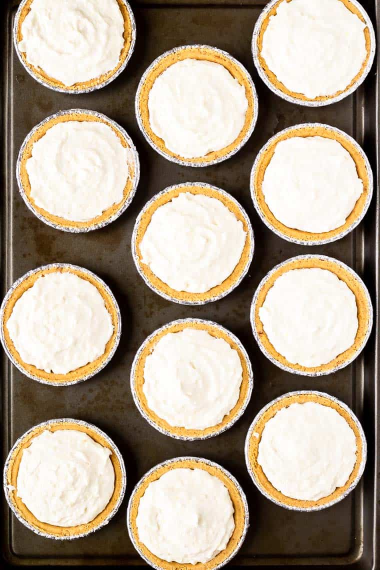 12 mini lemon cheesecakes on a baking sheet