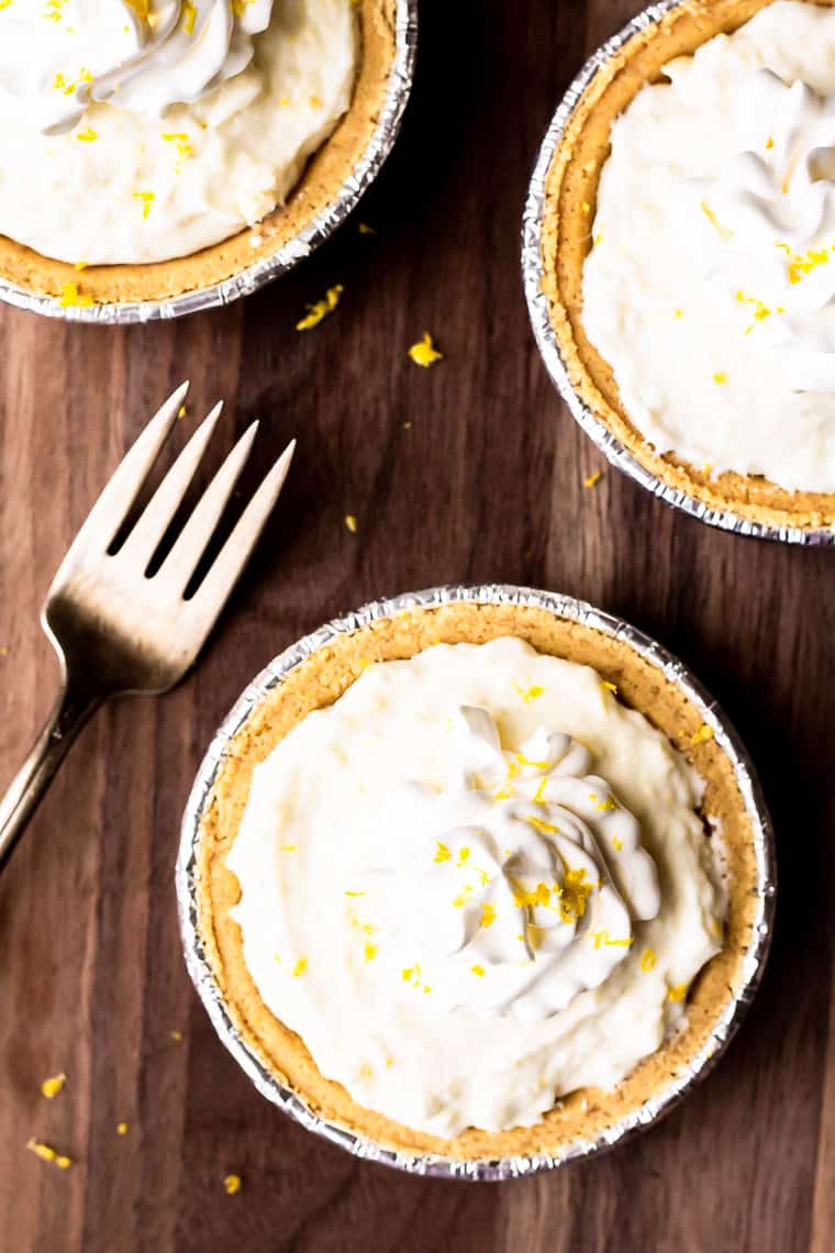 Overhead of 3 mini cheesecakes with a fork next to them on a wood background