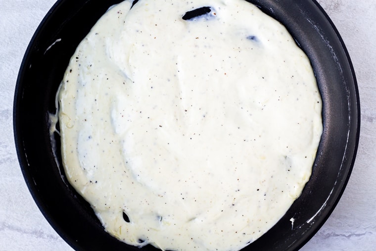 Parmesan peppercorn sauce in a black skillet over a white background