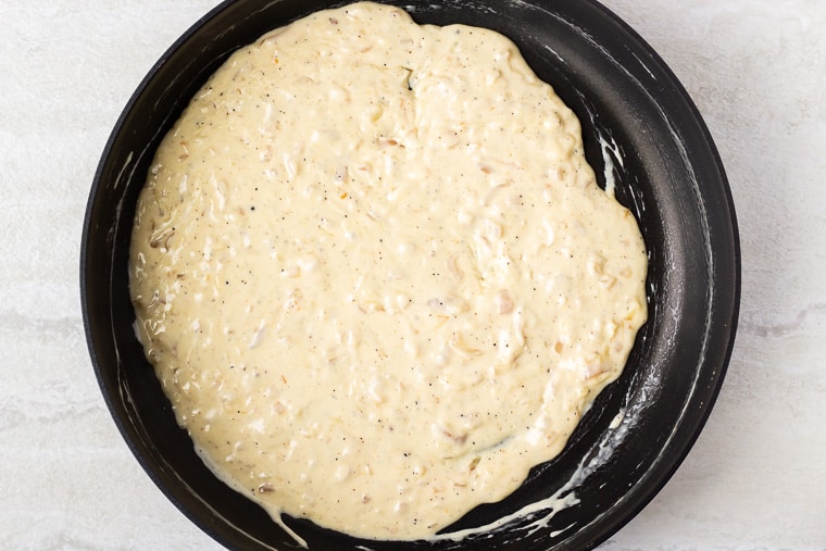 Cheese sauce in a black skillet over a white background