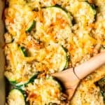 Close up of keto zucchini gratin with a wood spoon lifting some up