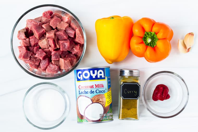 Ingredients to make coconut curry beef on a white background