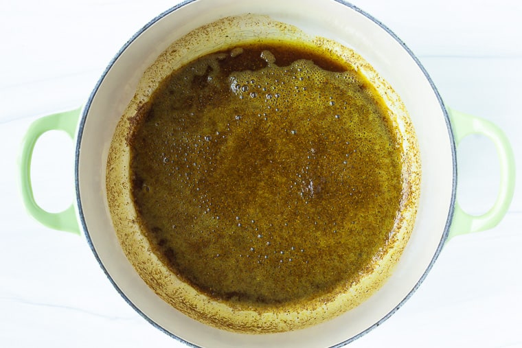 Curry oil in a dutch oven over a white background