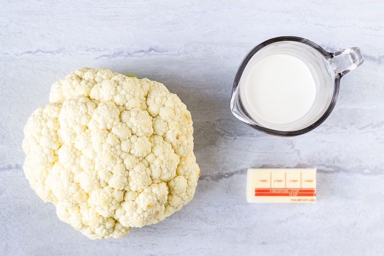 Ingredients to make creamy mashed cauliflower on a white background