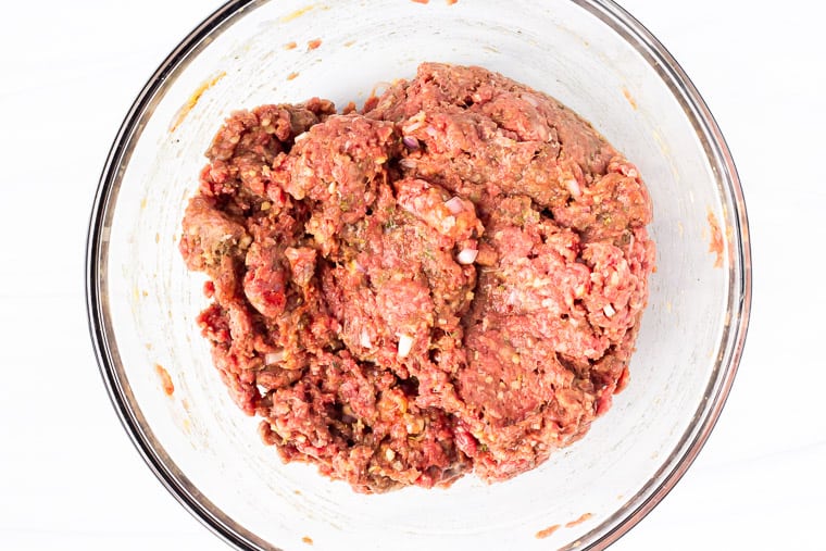 Meatloaf mixture in a glass bowl over a white background