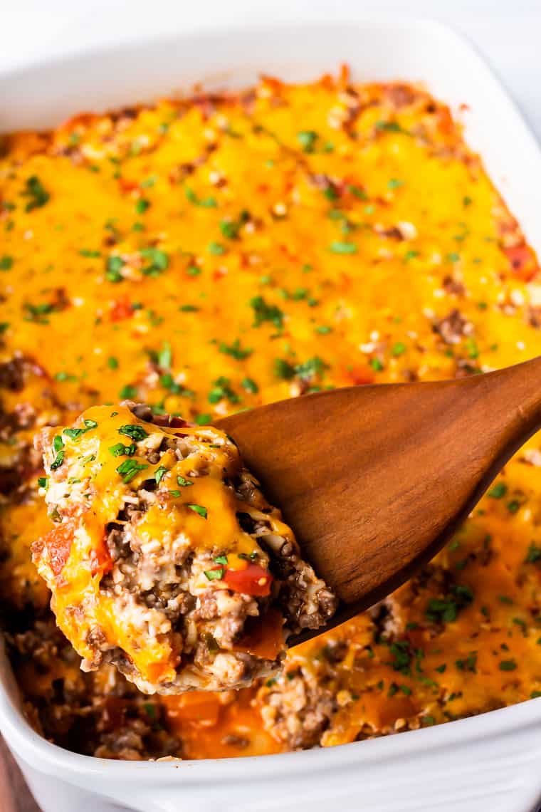 close up of a scoop of ground beef mexican casserole being lifted up with a wood server