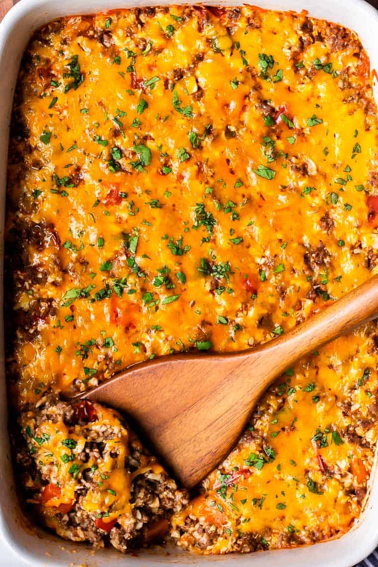 Overhead of a keto mexican casserole with a scoop partially lifted up with a wood turner